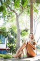 A woman sitting on a wooden deck next to a tree.