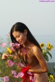 A naked woman standing in a field of flowers.