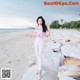 A woman standing on a beach next to some rocks.