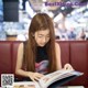 A woman sitting at a table reading a book.