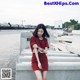 A woman in a red dress sitting on a concrete wall.