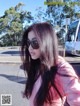 A woman with long black hair wearing sunglasses on the street.