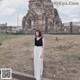 A woman standing in front of a large stone building.