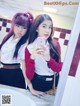 Two young women taking a selfie in a bathroom mirror.