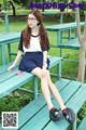 A woman sitting on a bench in a park.