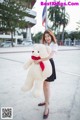 A woman holding a large white teddy bear with a red bow.