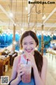 A woman sitting at a table with a drink in her hand.