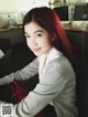 A woman with long red hair sitting at a desk.