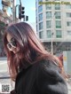 A woman with long red hair standing on a city street.