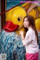 A woman standing in front of a painting of a yellow duck.