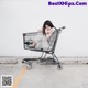 A woman sitting in a shopping cart with her head in her hands.