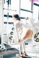 A woman in a white shirt and leggings standing in a gym.