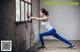 A woman in a white tank top and blue leggings doing a squat.