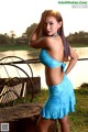 A woman in a blue bikini posing by the water.