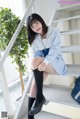 A woman in a school uniform sitting on a set of stairs.