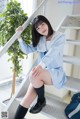 A woman in a school uniform is sitting on the stairs.