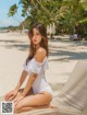 A woman in a white bathing suit sitting on a beach.