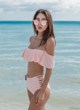 A woman in a pink bikini standing in the ocean.