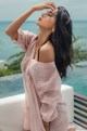 A woman in a pink and white striped dress posing by the ocean.