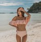 A woman in a pink bikini standing on a beach.