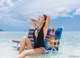 A woman in a black swimsuit sitting on a beach chair.