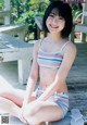 A woman in a bikini sitting on a wooden bench.