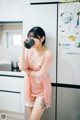 A woman in a pink robe drinking from a cup.