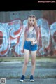 A young woman standing in front of a graffiti covered wall.