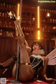 A woman in fishnet stockings is sitting on a pole.