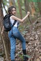 A woman with a backpack and a stick in the woods.