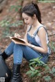 A woman sitting on the ground writing in a notebook.