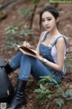 A woman sitting on the ground writing in a notebook.