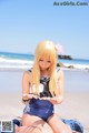 A woman in a sailor outfit sitting on the beach.