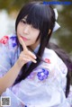 A woman in a kimono sitting by a body of water.