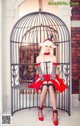 A woman in a red and black dress sitting in a cage.