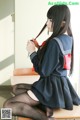 A woman in a school uniform sitting on a desk.