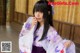 A woman in a purple and white kimono posing for a picture.