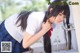 A woman in a school uniform drinking water from a faucet.