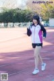 A woman in a pink and white jacket and black shorts on a track.