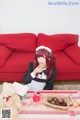 A woman sitting on a red couch eating a piece of cake.