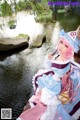 A woman in a blue and pink dress sitting on a wooden bridge.