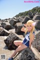 A woman in a blue and white outfit sitting on a rock.