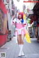 A woman in a pink and white outfit is walking down the street.