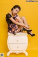 A woman sitting on top of a white dresser.