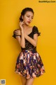 A woman in a black top and a floral skirt posing for a picture.