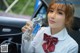 A woman in a school uniform holding a bottle of water.