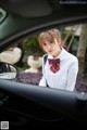 A woman in a white shirt and red bow tie sitting in a car.