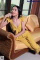 A woman sitting on a couch in a yellow dress.