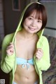 A woman in a green hoodie is posing for a picture.