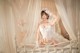 A woman in a white lingerie sitting on a bed.